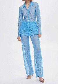 Ensemble de chemise et pantalons en dentelle bleu ciel, comprenant une chemise à boutons avec des manches longues et un pantalon évasé avec une texture transparente et un motif floral.