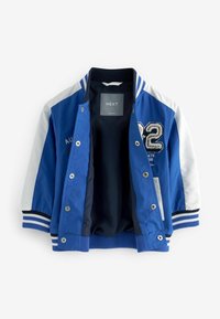 Veste bomber bleue avec manches blanches, poignets côtelés rayés, boutons-pression et numéro brodé "82" sur le devant. Intérieur doublé en marine.