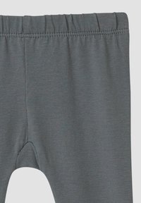 Graue Leggings mit einer glatten, dehnbaren Textur. Sie verfügen über einen elastischen Bund und passen eng an den Beinen an, laufen an den Knöcheln schmal zu.