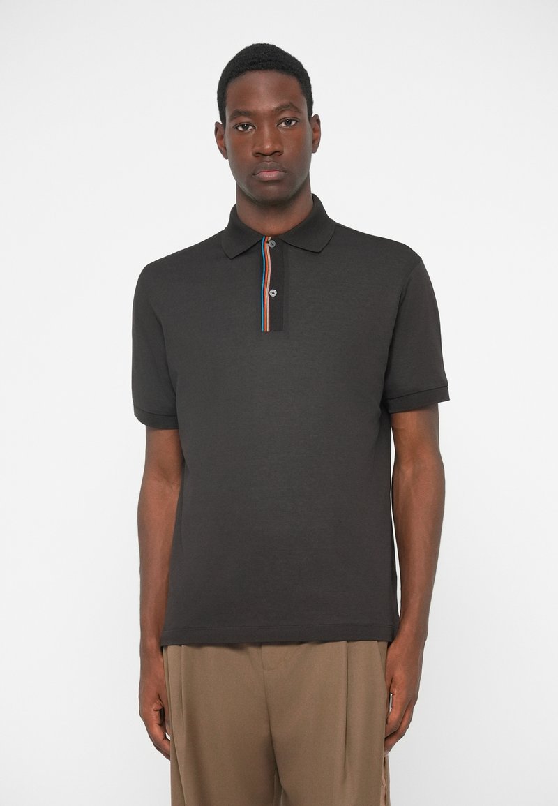 Μαύρο πόλο μπλουζάκι από βαμβάκι, με αντιθέτου χρώματος �γιακά με κόκκινες, μπλε και λευκές ρίγες, κοντά μανίκια και κλείσιμο με κουμπί.