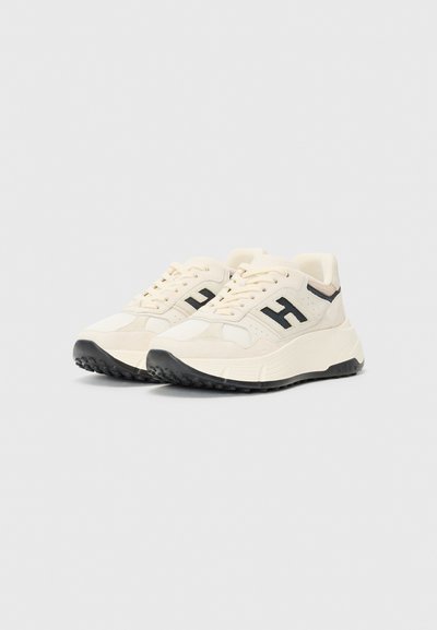 Witte sneakers met gestructureerde stof en zwarte accenten. Beschikt over een dikke zool en een prominent "H"-logo aan de zijkanten. Gestrikt ontwerp.