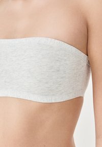 Top bandeau grigio senza spalline realizzato in un tessuto morbido e leggermente testurizzato, con una finitura liscia e un orlo curvo.