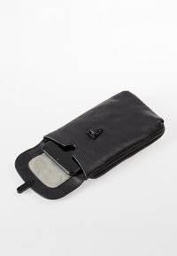 Borsetta per telefono in pelle nera con chiusura a zip, dotata di un rivestimento interno testurizzato e di un'esterno con patta e un piccolo dettaglio in metallo.