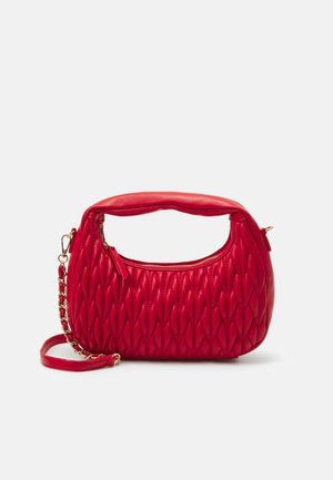 Rote gesteppte Handtasche mit einem gebogenen gepolsterten Griff, goldener Kettenriemen und oberem Reißverschluss auf weißem Hintergrund.