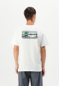 Witte katoenen t-shirt met een grafisch ontwerp op de rug met groene golven, grijze texturen en gestileerde tekst. Korte mouwen en een standaard pasvorm.