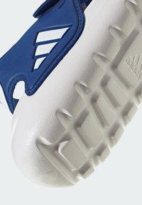 Niebieska syntetyczna cholewka z białymi akcentami i wzorem trzech pasków. Gruba biała gumowa podeszwa z fakturą zapewniającą przyczepność oraz detal z logo.