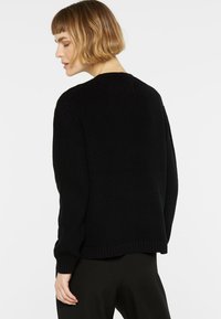 Schwarzer Strickpullover mit lockerer Passform, gerippten Bündchen und Saum, strukturiertem Material und rundem Ausschnitt.