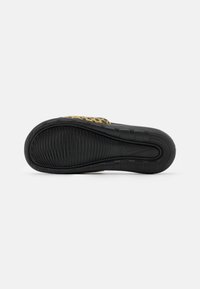 Melnas kedas ar strukturētu protektoru, pie kura aizmugures ir dzeltena un melna leopardu raksta akcentācija, bet centrā atrodas Nike logo.