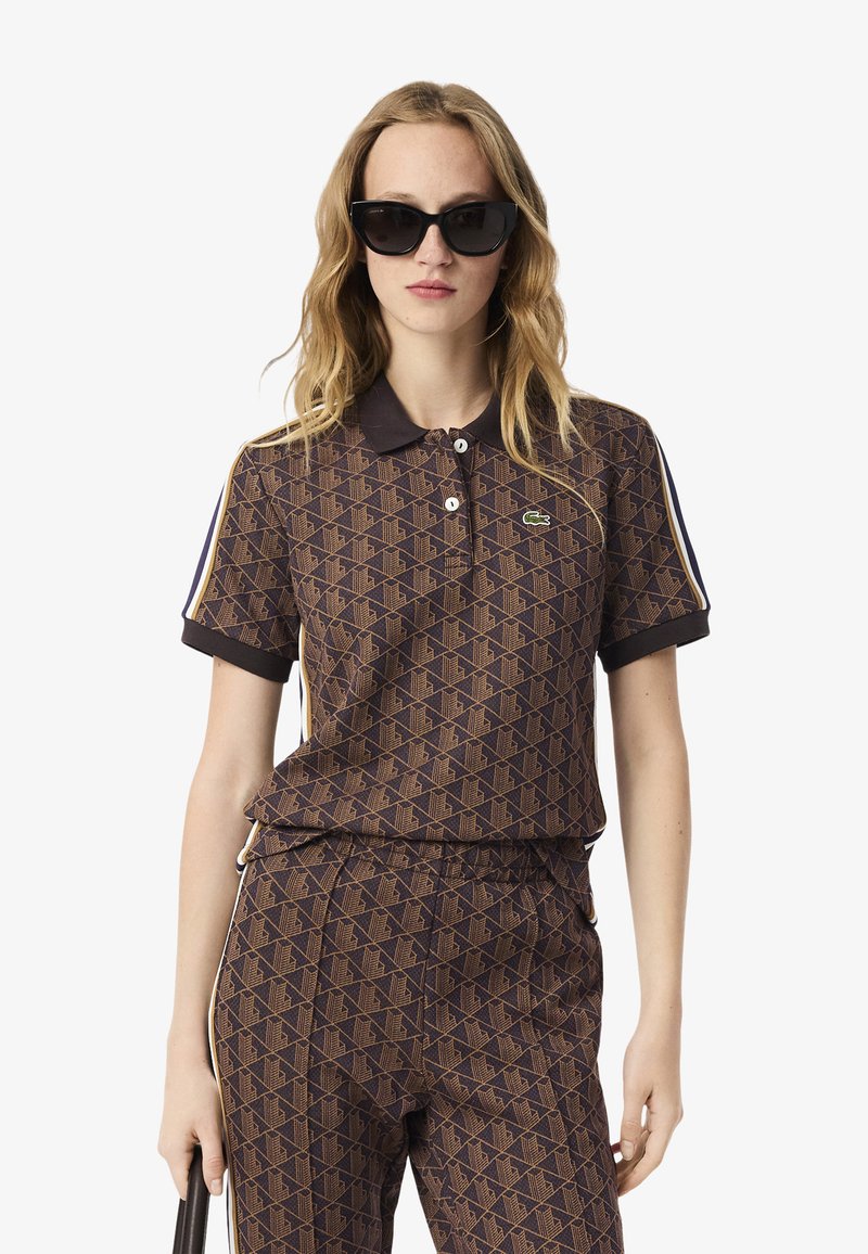 Braun gemustertes Poloshirt mit Kragen, zwei Knöpfen und Lacoste-Logo. Mit kontrastierenden gestreiften Ärmeln und einem lockeren Schnitt.