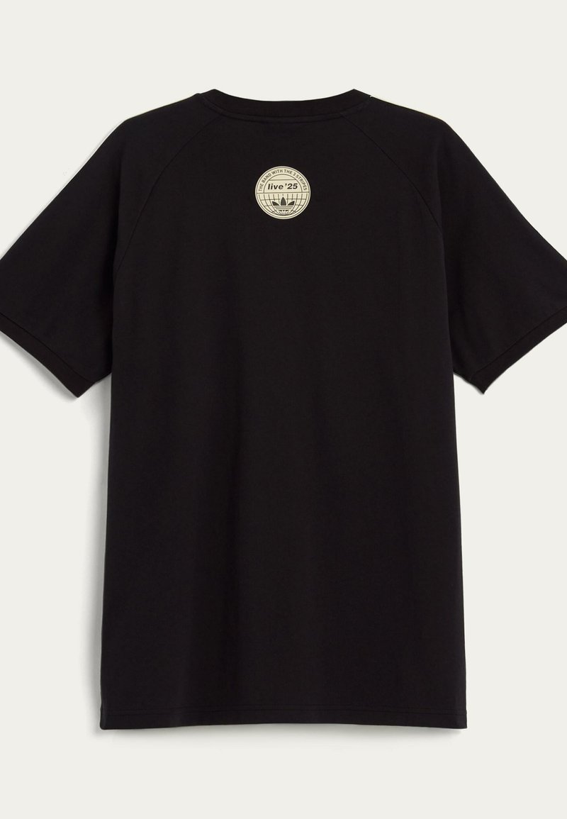 T-shirt nera a maniche corte con un piccolo logo circolare beige vicino al colletto sul retro, che presenta testo e un design grafico.