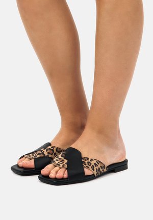 Sandali piatti neri con pannello a stampa leopardata e design a fascia larga. Texture morbida, stile open-toe e un tacco sottile.