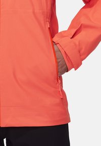 Water-resistant, bright coral jacket featuring a zipped pocket and adjustable cuffs. Smooth texture and lightweight design for outdoor use.