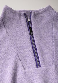 Lavender Pullover mit hohem Kragen, ausgestattet mit einem vertikalen Reißverschluss und geripptem Textur, akzentuiert durch dunkle Reißverschlussdetails und flache Nähte.