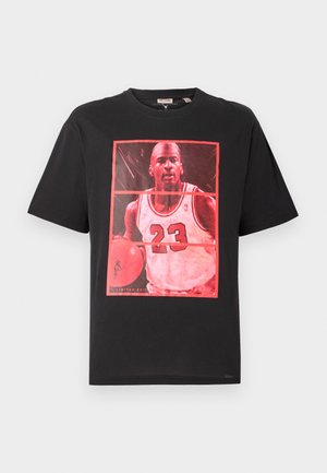Camiseta de algodón negra con un gran gráfico rojo de un jugador de baloncesto con el número 23, enmarcado en un rectángulo.