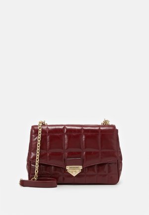 Sac à main en cuir rouge matelassé avec une bandoulière chaîne en or, doté d'une fermeture métallique et d'une finition brillante. La surface présente une texture rembourrée et un motif géométrique.