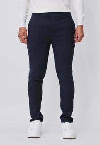 Pantalon marine coupe slim, à la texture lisse et fermeture par bouton. Associé à des baskets blanches pour un look décontracté.