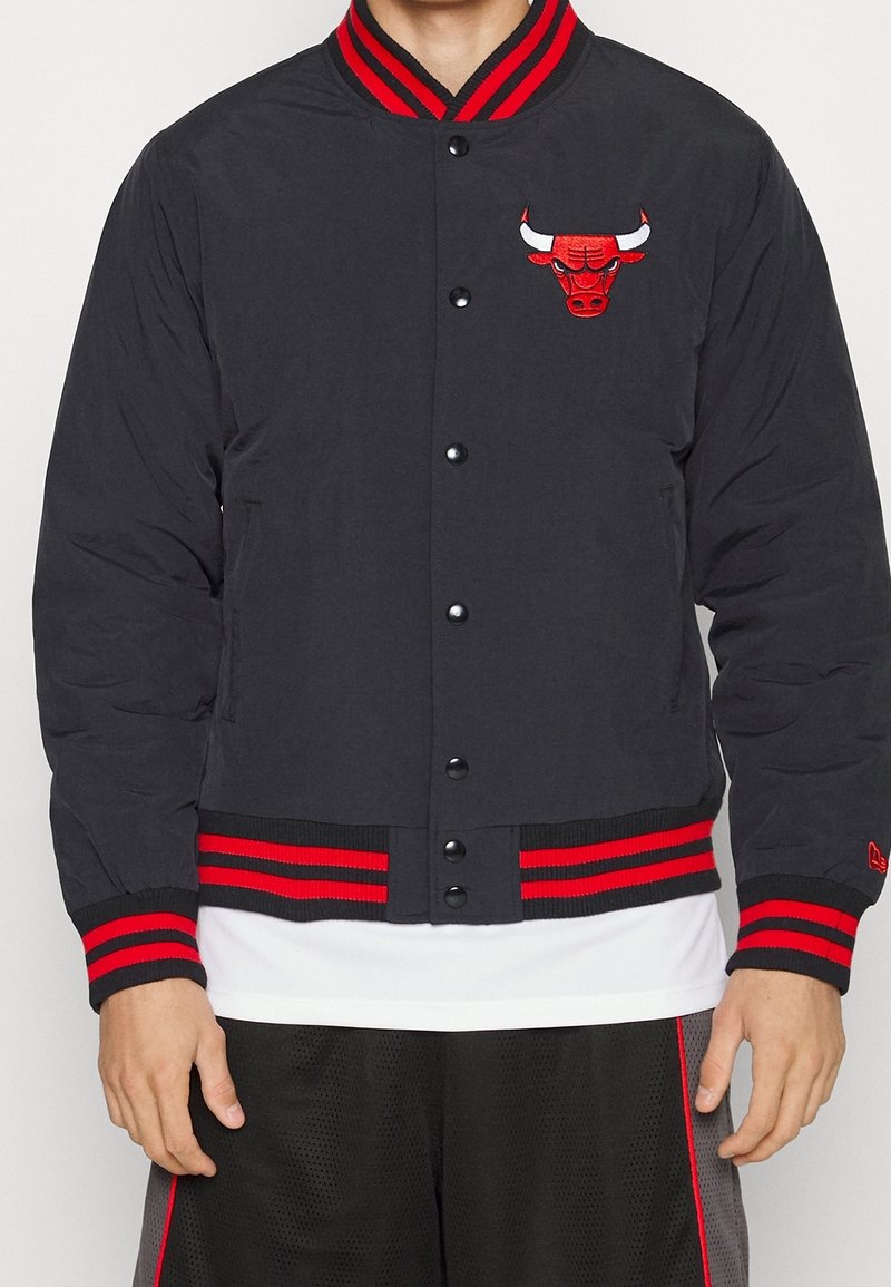 Schwarze Bomberjacke mit rot gestreiften Bündchen und Saum, ausgestattet mit einem roten, gestickten Bullen-Logo auf der Brust und Druckknopfverschluss.