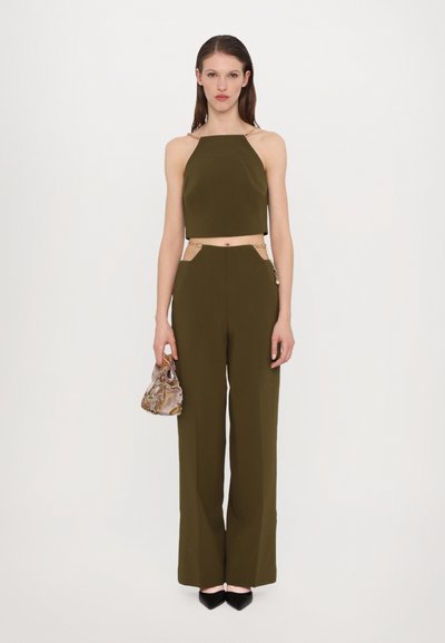 Costum din două piese de culoare verde măslin, cu un top fără mâneci și bretele cu lanț, asociat cu pantaloni largi. Împreună cu o geantă mini cu model.