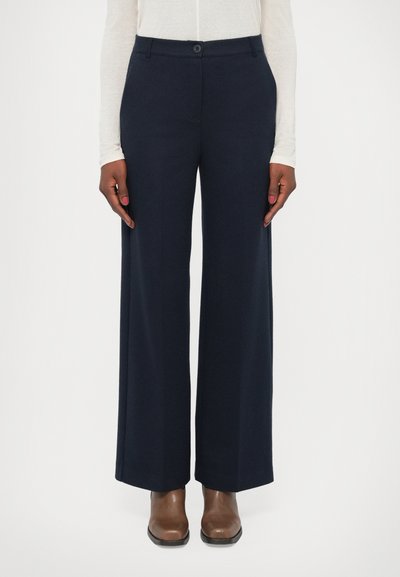 Navy wide-leg trousers made of soft fabric, featuring a button closure and side pockets. Paired with brown leather ankle boots.