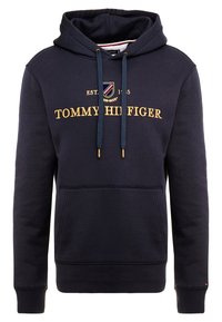 Sudadera con capucha de color azul marino, confeccionada en una suave mezcla de algodón. Presenta el texto dorado "TOMMY HILFIGER", cordones con puntas de metal y un bolsillo tipo canguro.