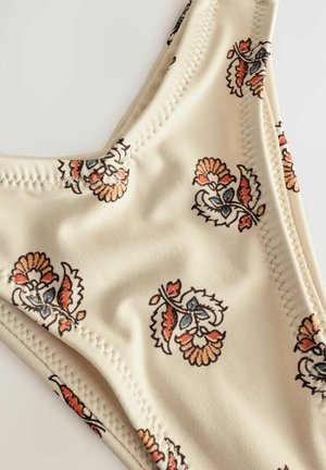 Bas de bikini beige avec des motifs floraux en orange, bleu et marron. Tissu lisse avec des coutures cousues et un design taille basse.