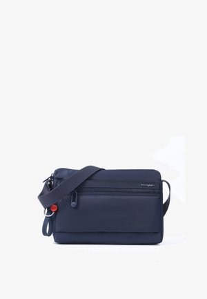 Kompakt navyblå crossbody taske med justerbar rem, forlommer med lynlås og Hedgren mærkelogo på hvid baggrund.