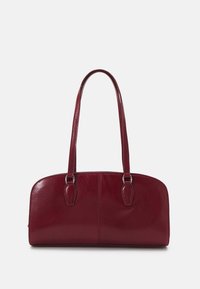 Červená kožená kabelka s hladkým povrchem, zaobleným tvarem a dvěma dlouhými uchy. Obsahuje jemné prošívání a elegantní design.
