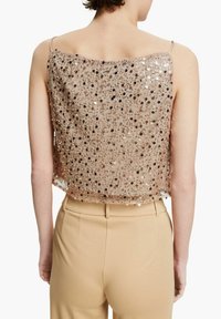 Beadad topp i beige med fyrkantig halsringning och tunna band; smyckad med glänsande paljetter som ger en texturerad, glittrande yta.