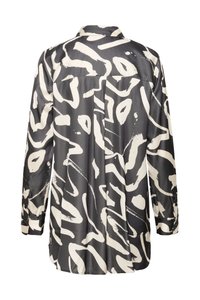 Mustvalge satiinsärk abstraktse mustriga, pikkade varrukate, krae ja nööbitavate mansettidega, seljal yoke-detailiga.