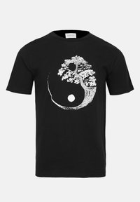Black cotton t-shirt featuring a white yin-yang design with a tree in place of the classic symbol, depicting intricate details and texture.