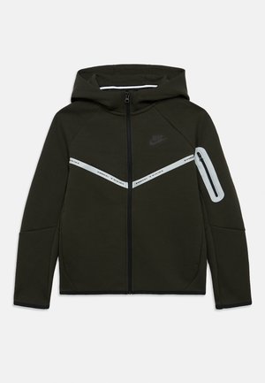 Tmavozelená mikina na zips s kapucňou, ktorá má biele diagonálne pruhy cez hrudník a bočné vrecko na zips. Mäkká textúra a atletický dizajn.