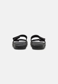 Sandales noires avec deux sangles ajustables ; fabriquées en caoutchouc avec une semelle intérieure texturée et une semelle de marque arborant le logo "Quiksilver."