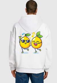 Fehér hoodie, színes grafikával, amelyen két napszemüveget viselő, táncoló és italt tartó mesebeli citrom látható. Puha anyag, lazább fazon.