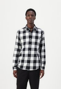 Zwart-wit geblokte langemouwen overhemd met een button-down kraag en knopen aan de voorkant, gemaakt van lichtgewicht stof, met contrasterende grote vierkanten.