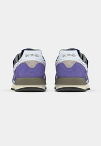 Purpursarkanas, baltas un pelēkas Reebok sporta kurpes, skatītas no papēža puses uz baltas fona.