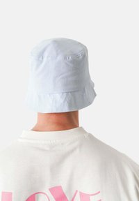 Jasnoniebieska czapka z szerokim rondem, wykonana z miękkiego materiału. Tył ma prosty, bezszwowy fason bez widocznych elementów metalowych ani akcentów.