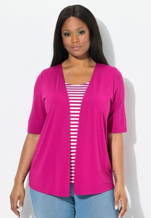 Fuchsia open-front cardigan met korte mouwen, gedragen over een wit en rood gestreepte top. Gekocht met lichtblauwe denim jeans.