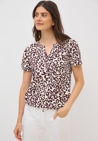 Top de manga corta en crema con estampado de leopardo púrpura, con escote en V y ajuste relajado. Tejido suave y textura sutil.