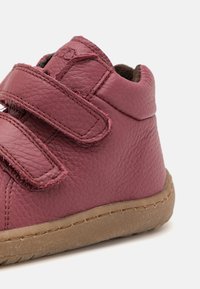 Pantof maiou din piele burgundy cu o suprafață texturată, având două curele Velcro reglabile și o talpă din cauciuc maro.