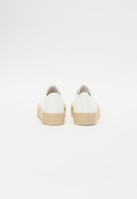 White canvas shoes with a rounded toe and woven jute sole. Simple, clean design with no visible patterns or hardware details.