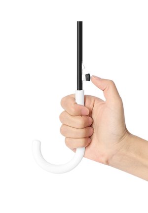 Hand pressing black button on white curved-handle umbrella shaft against white background.