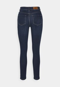 Jeans ajustados de color azul oscuro con una textura suave, que cuentan con una cintura alta, dos bolsillos traseros y un sutil detalle de costura.