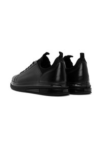 Sneaker neri in pelle con una trama liscia, forma arrotondata e colli imbottiti. Caratterizzati da lacci piatti e una suola ammortizzata con dettagli.
