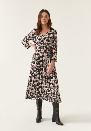 Vestito a portafoglio in tessuto stampato con disegni astratti in nero, rosso e bianco. Maniche lunghe, cintura in vita e orlo di lunghezza media.