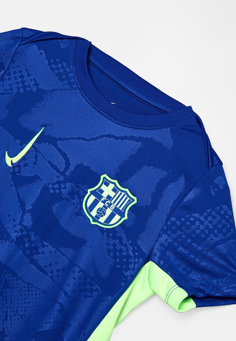 Camiseta de fútbol del FC Barcelona en azul y verde neón, con el logo de Nike y el escudo del club en la parte delantera, que presenta una textura de tela con patrón.