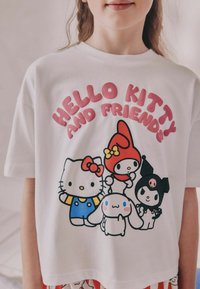 Biała bawełniana koszulka z krótkim rękawem, z kolorową grafiką przedstawiającą Hello Kitty i jej przyjaciół. Napis "HELLO KITTY AND FRIENDS" w kolorze różowym.
