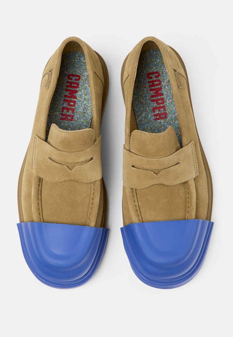 Mocassini in suede color tan con puntale in gomma blu. Presentano cuciture decorative e un design slip-on. Rivestiti con un tessuto colorato e maculato.