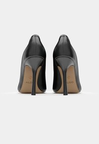 Scarpe nere con tacco alto, rifinite in pelle liscia, punta affusolata e sottile tacco a stiletto. Presentano un logo dorato discreto sulla soletta.