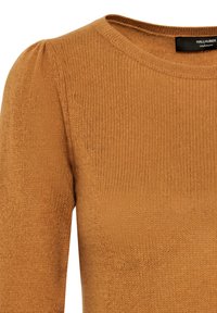 Närbild av en kamelbrun kashmirtröja med rund halsringning och subtila puffärmar.