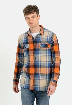Flannel skjorte med orange, blå og beige ternede mønstre. Den har to brystlommer, knaplukning foran og lange ærmer.